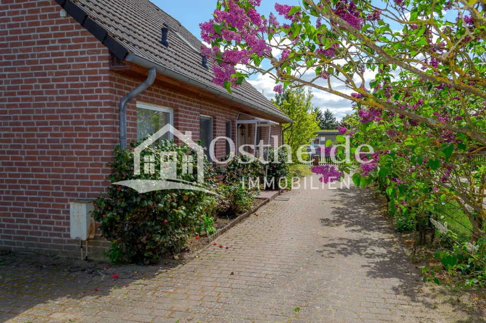 Blick aus dem Carport auf die gepflasterte Einfahrt und den einladenden Haupteingang des Klinker-Einfamilienhauses in Karwitz-Lenzen.