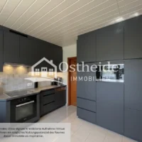 Digital möblierte Design-Küche der Immobilie in Karwitz mit Blick aus dem Essbereich auf eine moderne, dunkel gestaltete Küchenzeile.