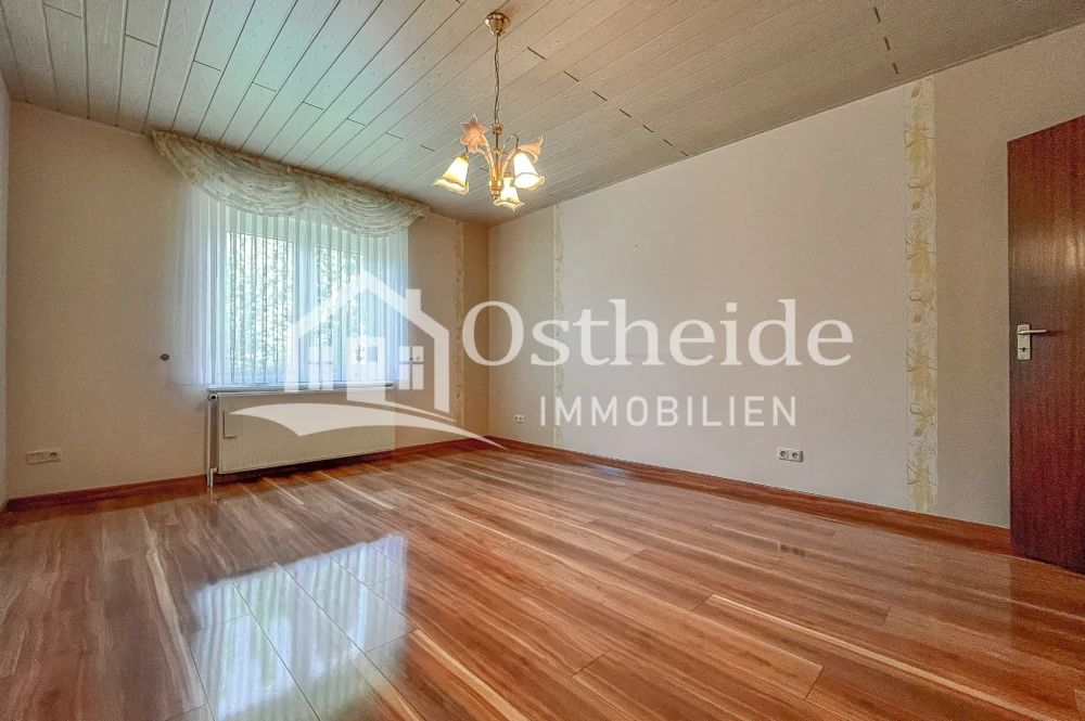 Helles Zimmer im Erdgeschoss der Immobilie in Karwitz, das als Schlafzimmer mit einem hochwertigen, hochglänzenden Parkettboden ausgestattet ist.