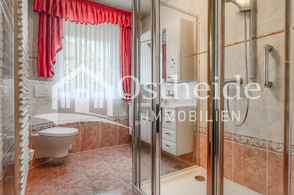 Hell eingerichtetes Tageslicht-Badezimmer der Immobilie in Karwitz mit hochwertigen Fliesen und einer großen, bodentiefen Dusche.